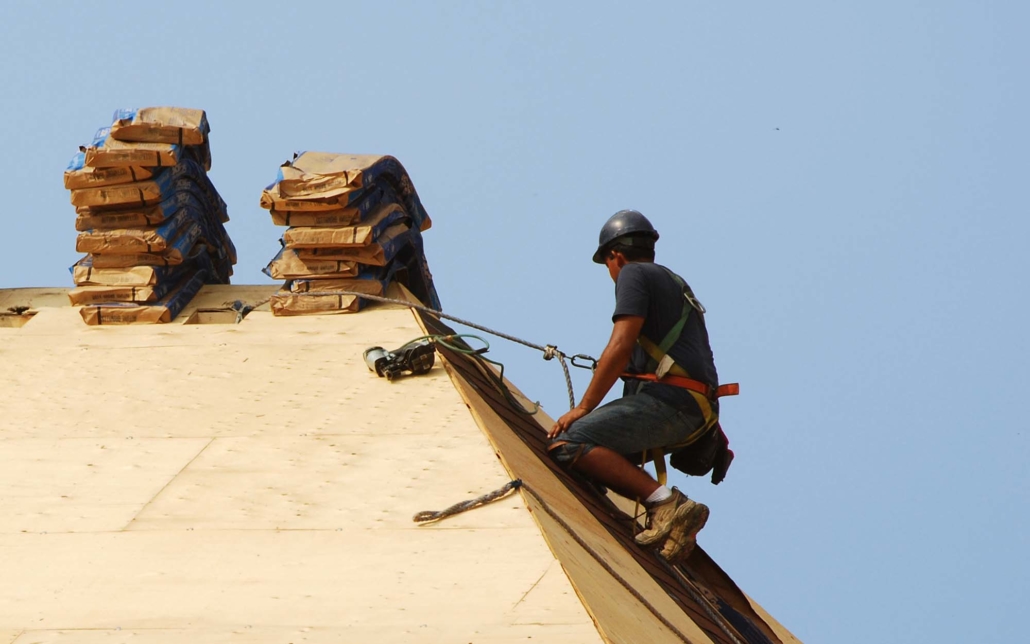 View of a roofing worker on steep slope rooftop