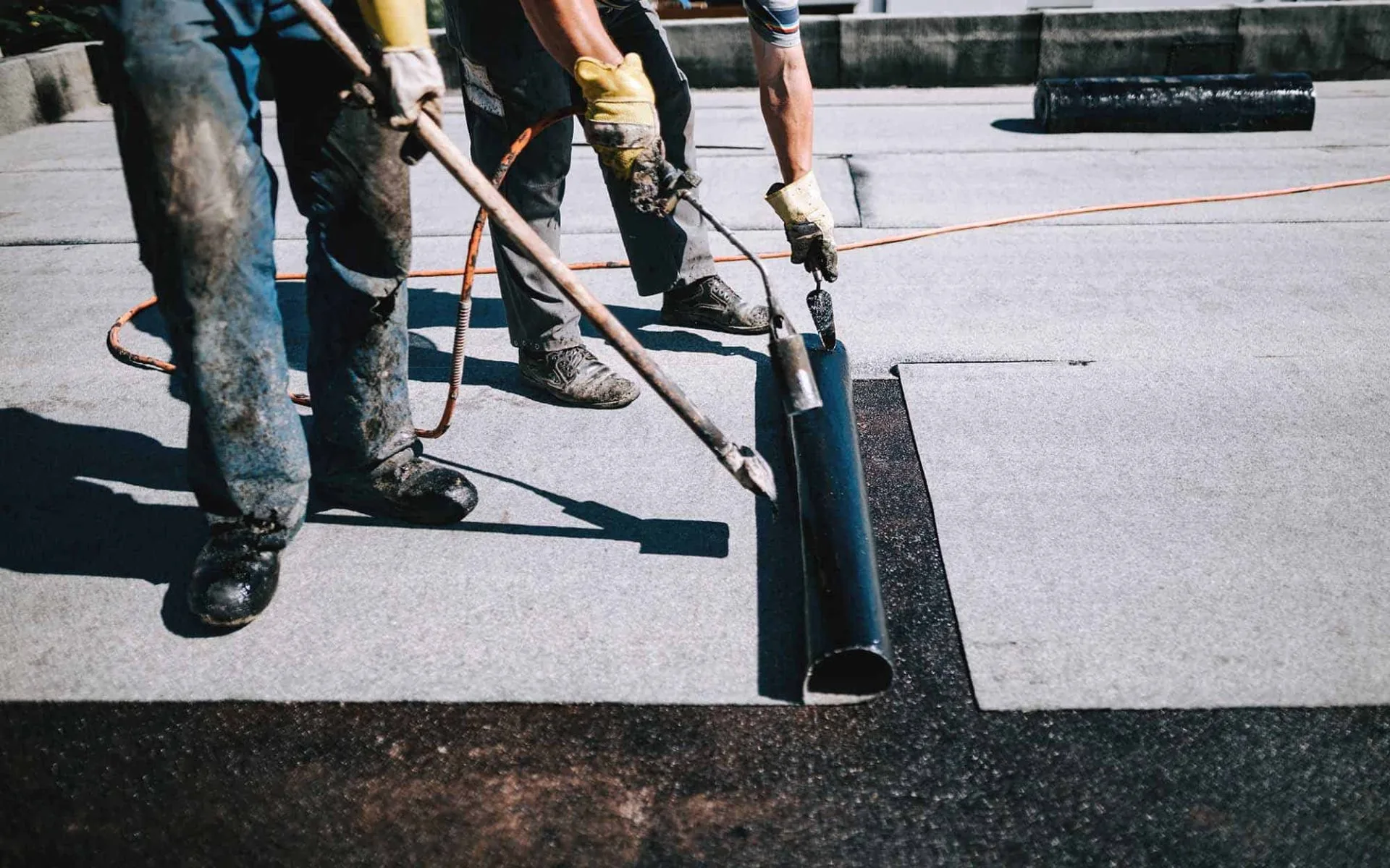 Two-roofers-applying-a-layer-of-asphalt-roofing